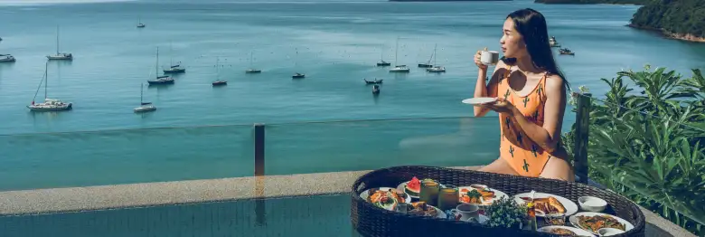 Woman enjoying food and drink overlooking a beautiful ocean harbor